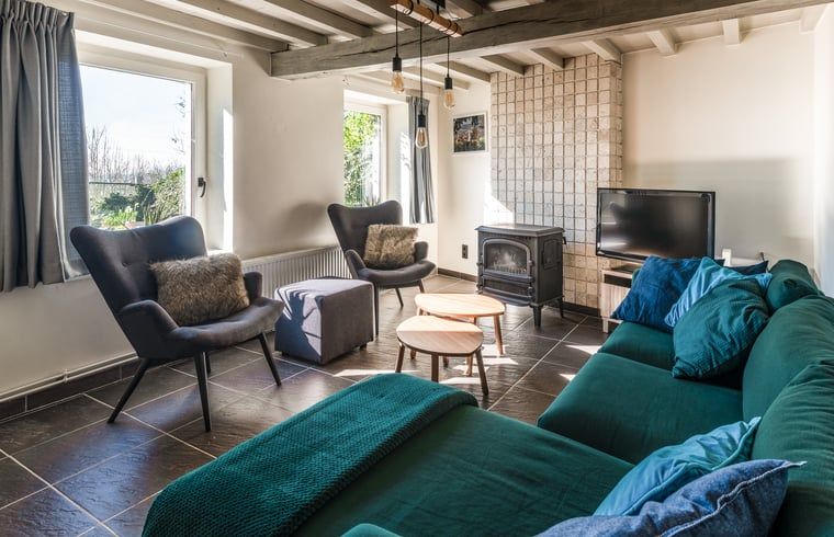 Gemuetliches Wohnzimmer im Ferienhaus in Ronse, Ostflandern, Belgien mit bequemer Sitzecke und Holzofen fuer eine gemuetliche Atmosphaere.