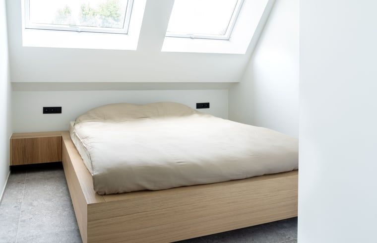 Schlafzimmer im Ferienhaus in Sint-Pieters-Leeuw, Flaemisch-Brabant, Belgien, mit bequemem Bett und Oberlichtern fuer natuerliches Licht.