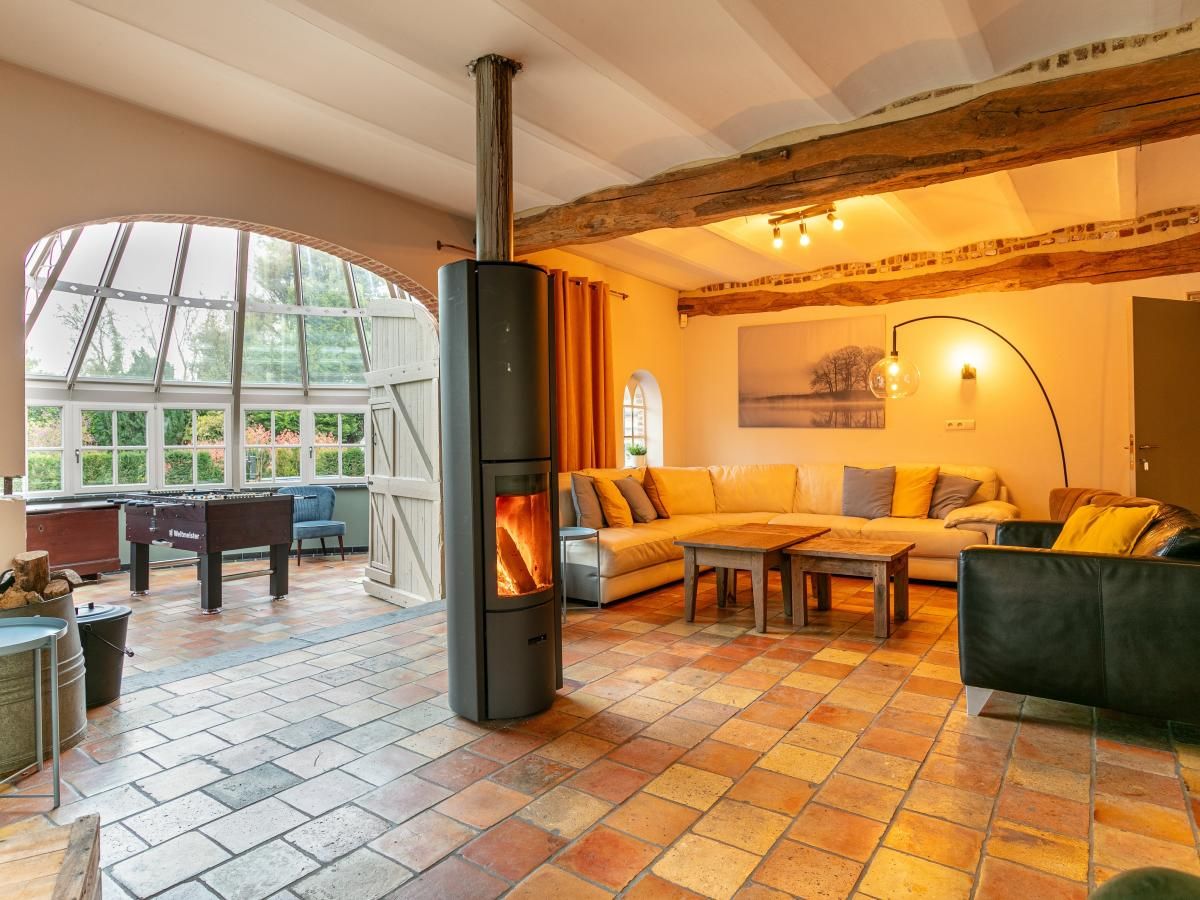 Gezellige woonkamer in vakantiehuis Alverwege, Merksplas, Antwerpen, met een warme haard en ruime zithoek voor ontspanning in een landelijke sfeer.