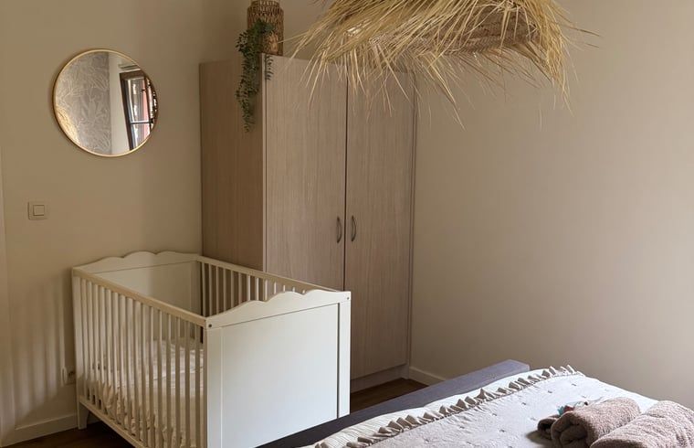 Cozy bedroom in Holiday Home in Merksplas, Antwerp, with a baby crib and natural decoration for a relaxing atmosphere.
