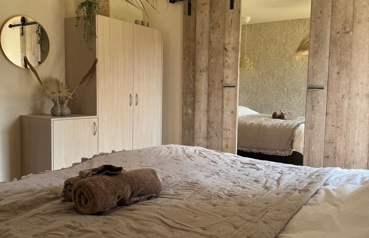 Attractive bedroom in Holiday Home in Merksplas, Antwerp, with wooden sliding doors and natural decoration for a restful stay.