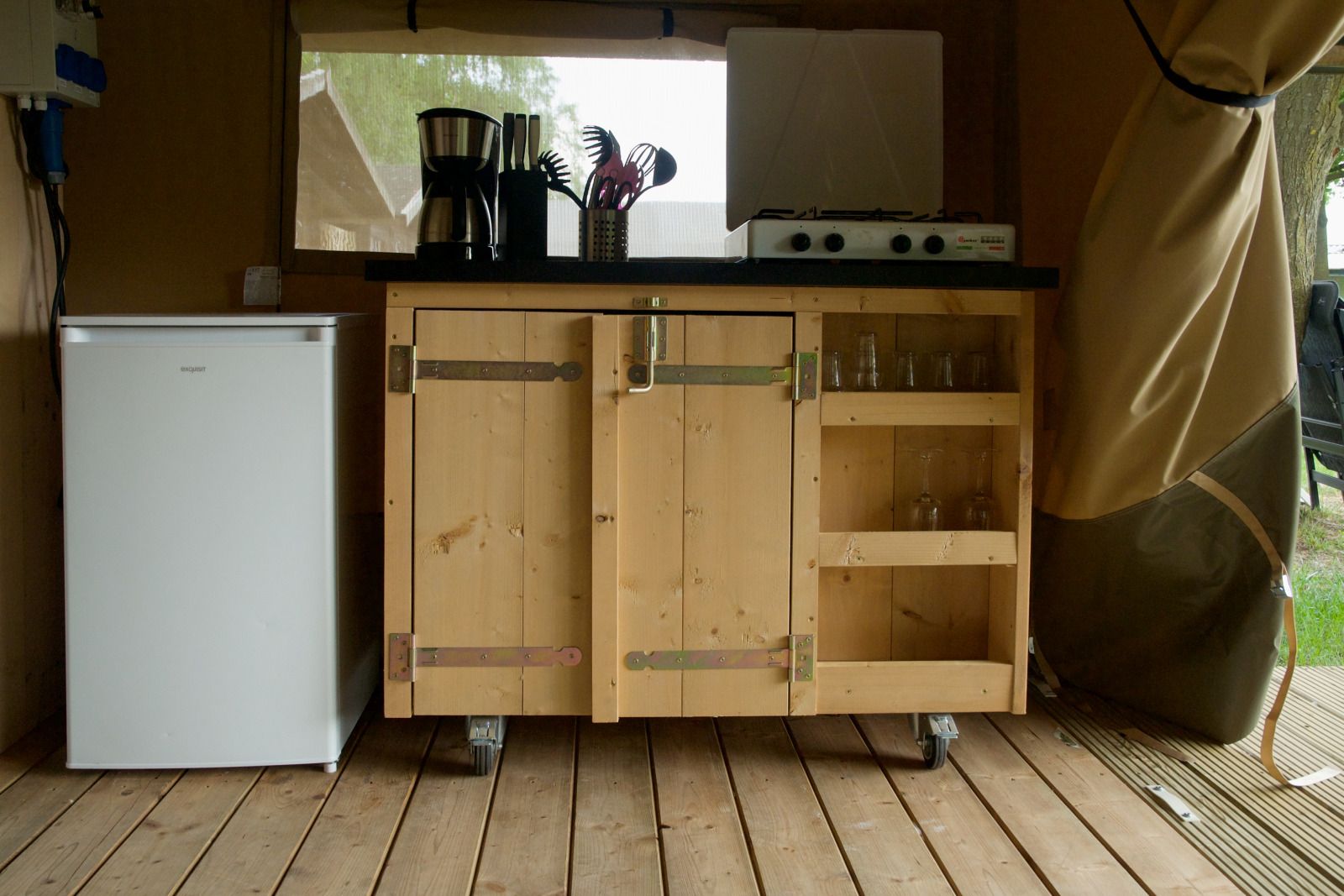 Kueche im Safari-Zelt, einer Glamping-Lodge in Brecht, Antwerpen, mit Kuehlschrank und Holzschrank fuer ein komfortables Ferienerlebnis.