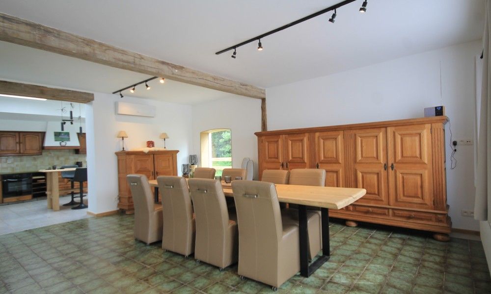 Geraeumiges Esszimmer im Huisje Nostalgie, Laakdal, Antwerpen, mit Holzmoebeln und moderner Beleuchtung.