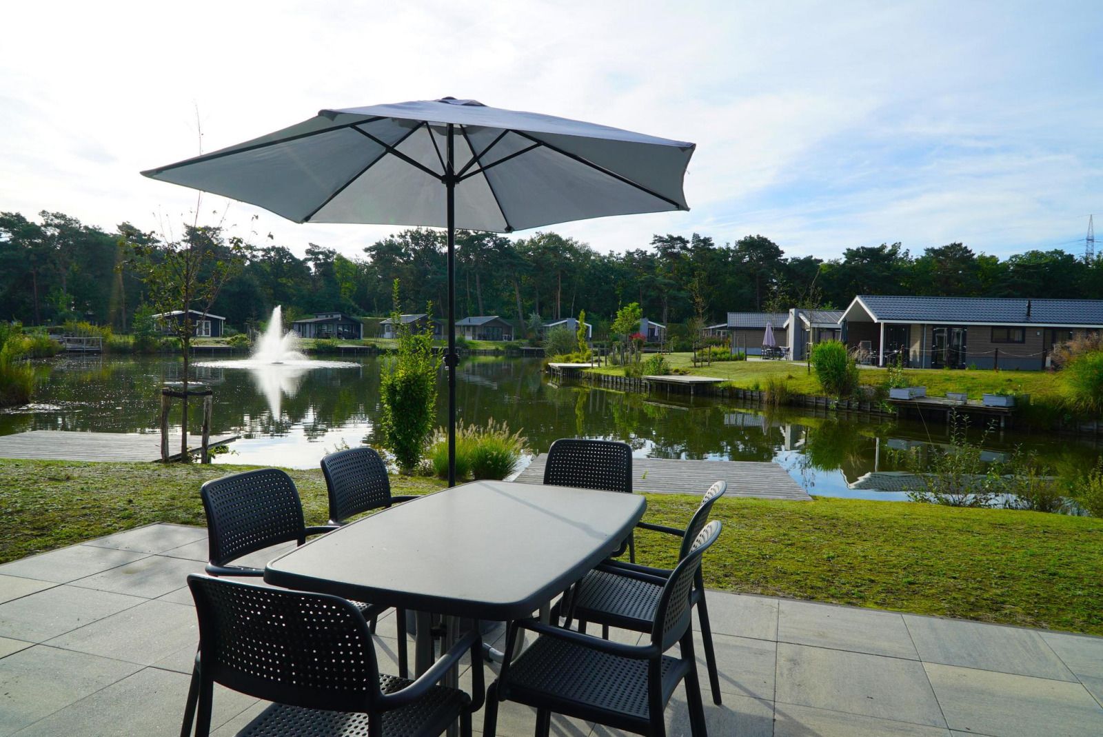 Enjoy the terrace of vacation home Velthorst in Mol, Antwerp, overlooking a serene pond and green surroundings.