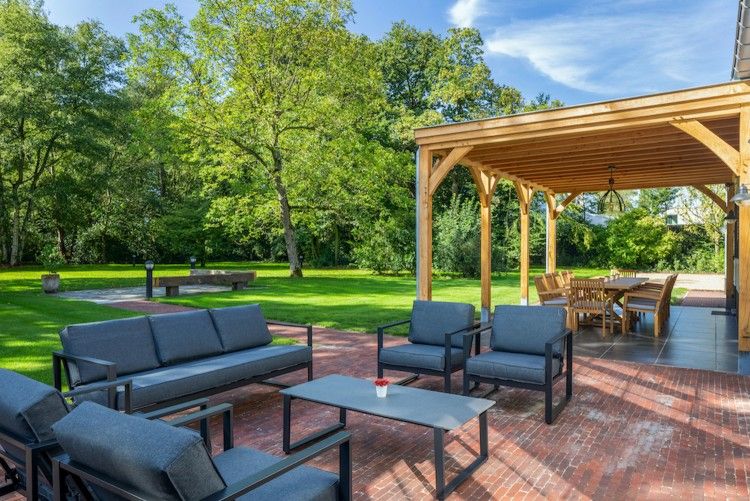 Mushoeve-Ferienhaus in Zoersel, Antwerpen mit gemuetlicher Sitzecke auf der Terrasse und gruenem Garten.
