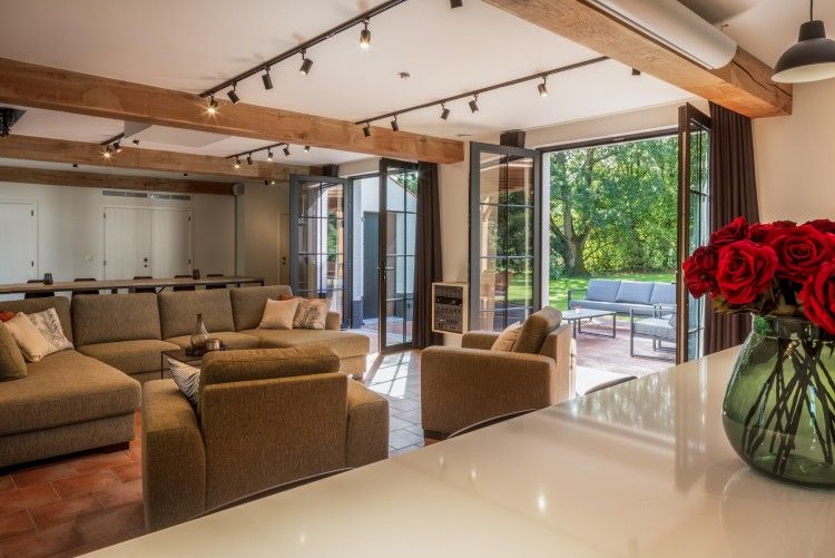 Stilvolles Wohnzimmer von Mushoeve in Zoersel, Antwerpen, mit grossen Fenstern und Gartenblick.