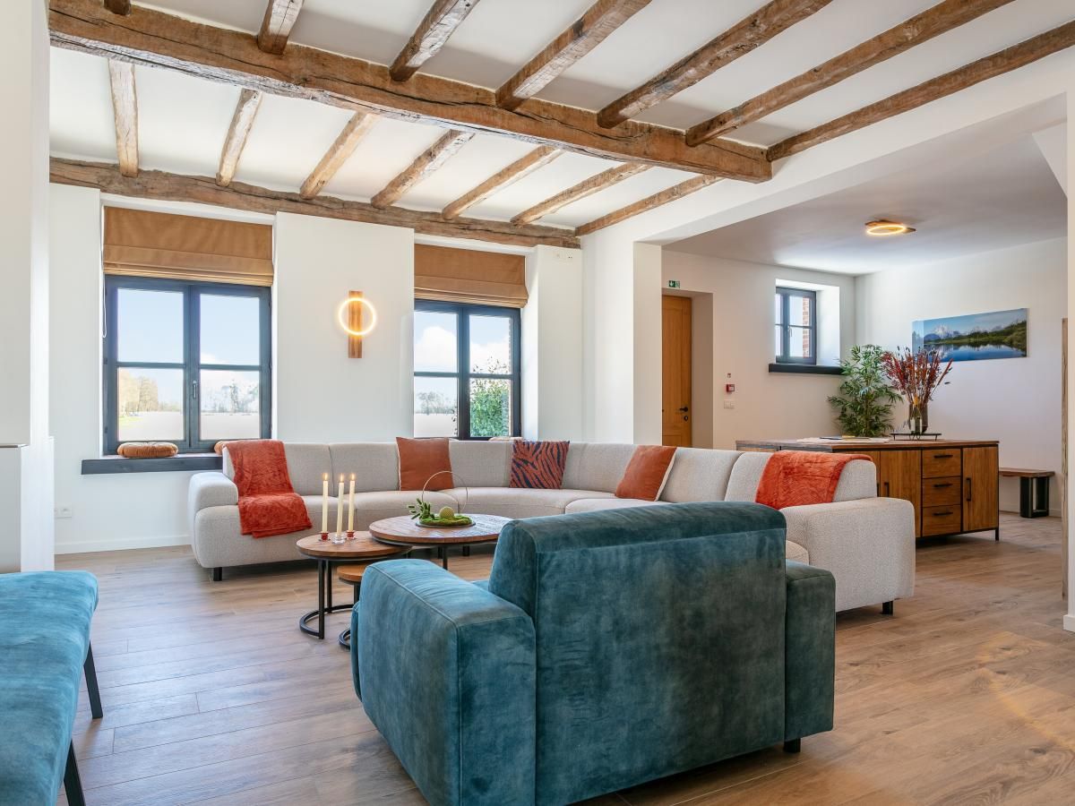 Cozy living room in Lindehoeve vacation home, Turnhout, with comfortable seating and wooden beams.