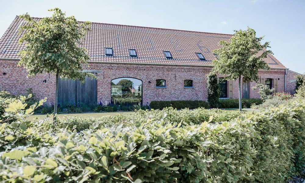 Driehoekshoeve vacation home in Kasterlee, Antwerp with charming brick exterior and green surroundings.