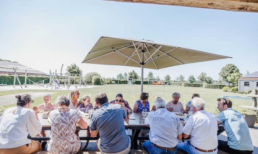 Group of people enjoy meal outside at Driehoekshoeve vacation home, Kasterlee, Antwerp.