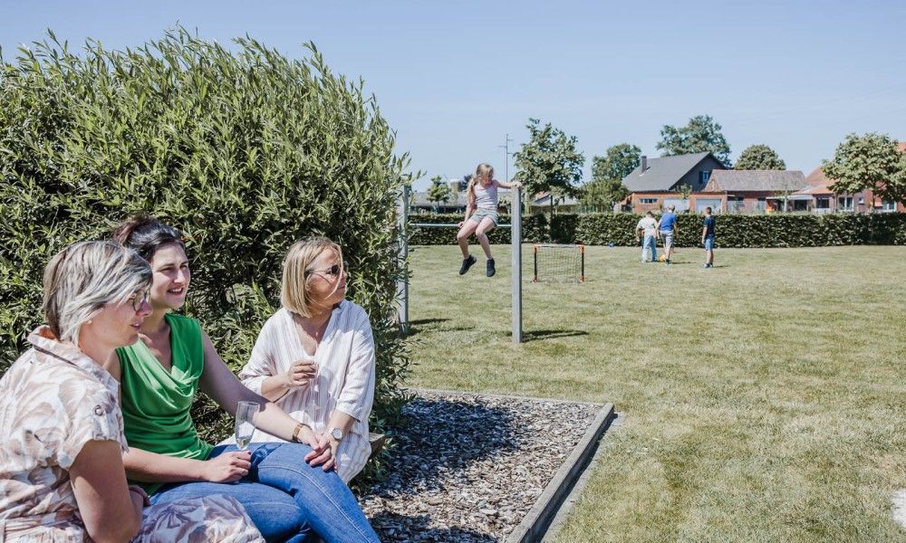 Women enjoy sun and views in the garden of Driehoekshoeve vacation home, Kasterlee, Antwerp.