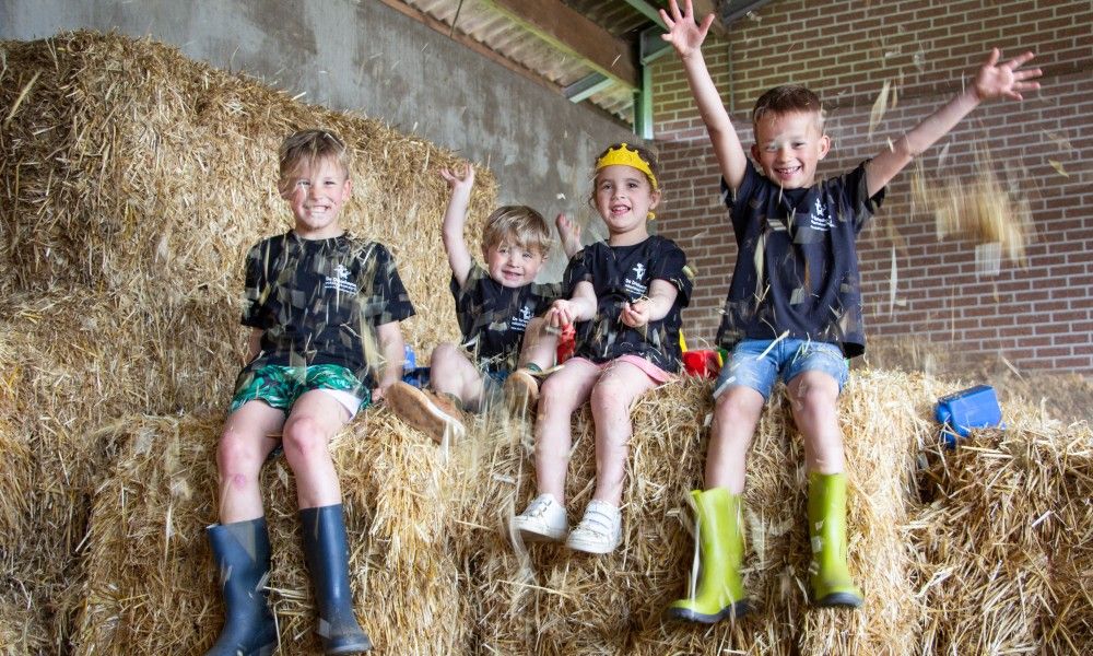 Kinder spielen mit Stroh in De Drieshoeve, einem Ferienhaus in Kasterlee, Antwerpen.