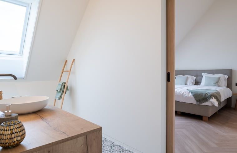 Modernes Schlafzimmer in einem Ferienhaus in Kasterlee, Antwerpen, mit stilvoller Einrichtung und viel natuerlichem Licht.