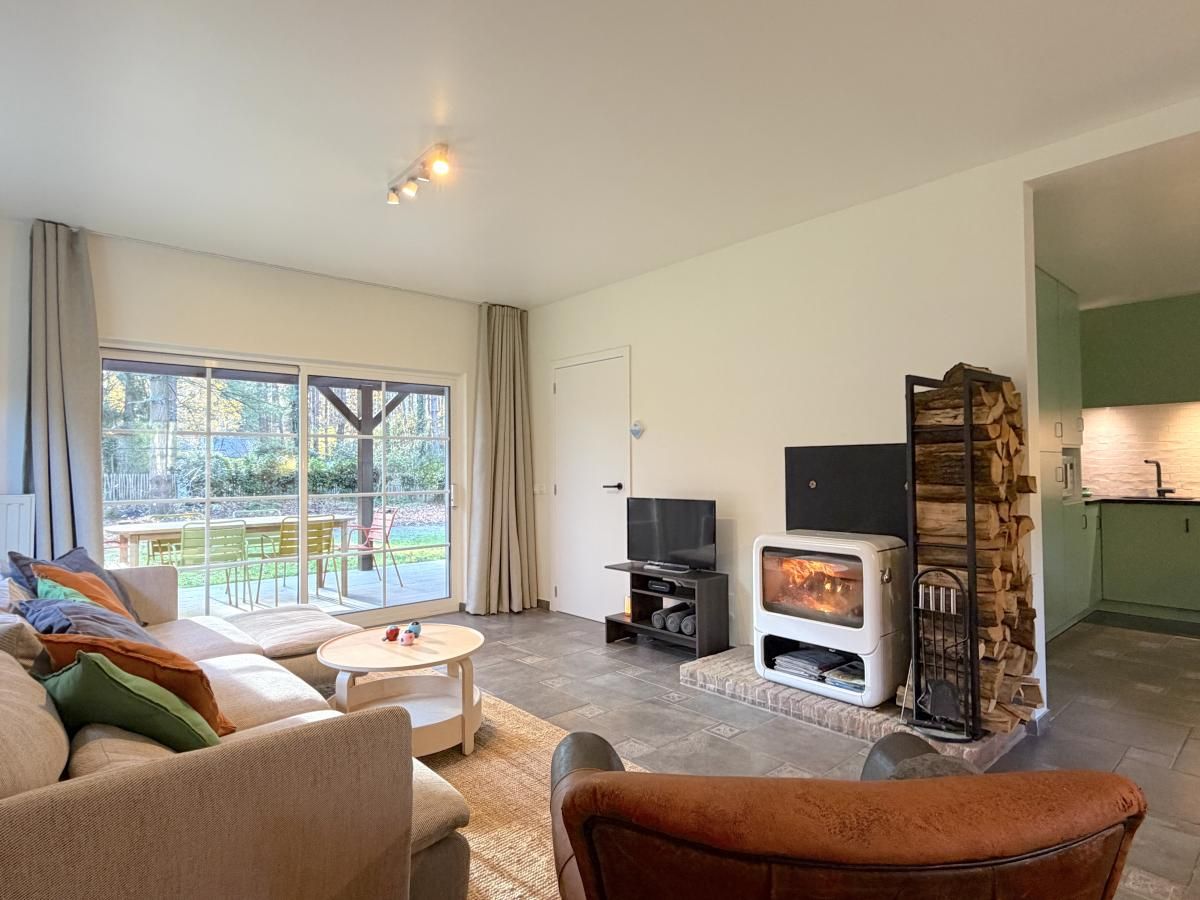 Cozy living room in Lierelodge vacation home, Oud-Turnhout, with wood stove and view of the green garden from the comfortable sitting area.