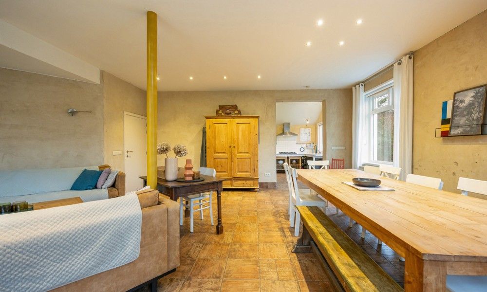 Ruime woonkamer van vakantiehuis De Morgenstond in Baarle-Hertog, Antwerpen, met gezellige zithoek en houten eettafel.