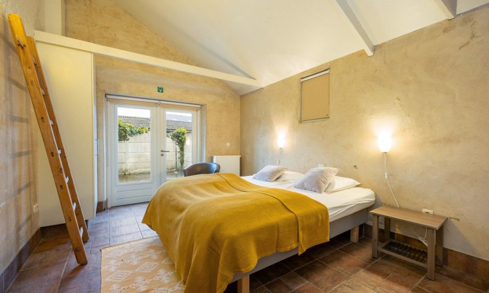 Sfeervolle slaapkamer in De Morgenstond vakantiehuis, Baarle-Hertog, Antwerpen, met comfortabele bedden en rustieke inrichting.