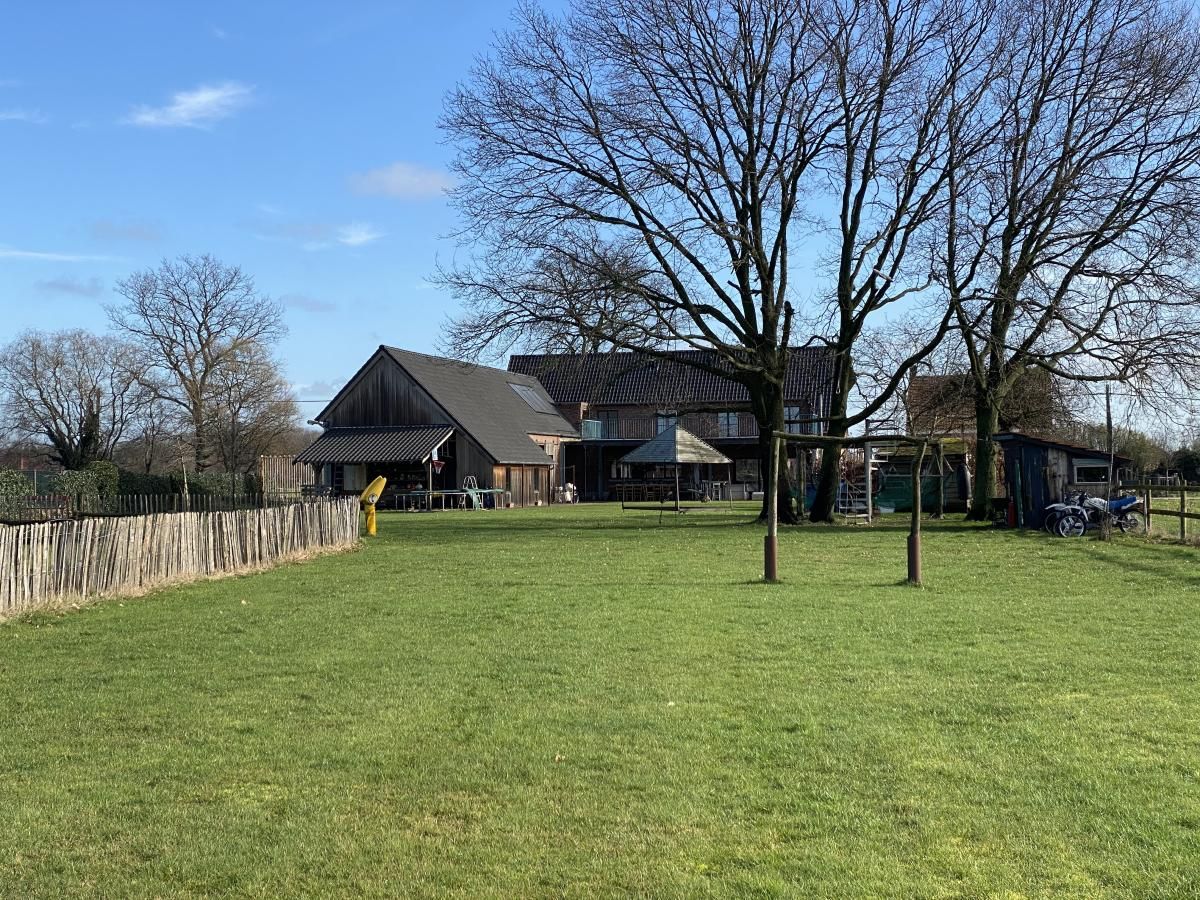 De Lieshoeve vakantiehuis in Arendonk, Antwerpen, Belgie met een uitgestrekt groen veld en bomen in een rustige landelijke omgeving.
