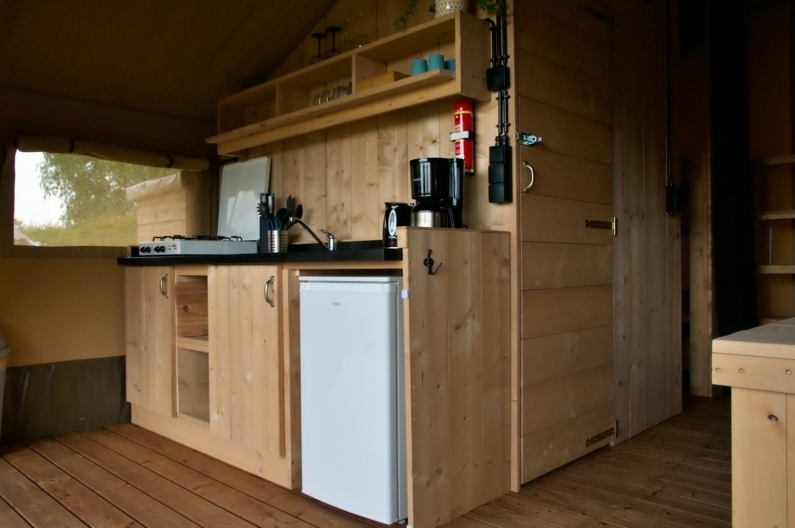 Cozy kitchen in Safari tent incl. plumbing, a glamping lodge in Lichtaart, Antwerp, Belgium, with wooden interior and modern amenities.