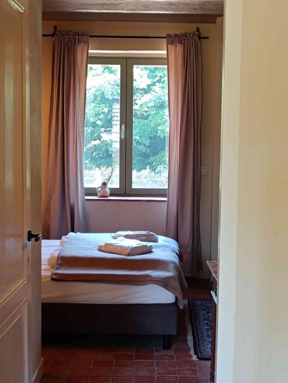 Gezellige slaapkamer in vakantiehuis Gemael1744, Voeren, Limburg, Belgie, met uitzicht op groene natuur door een groot raam.
