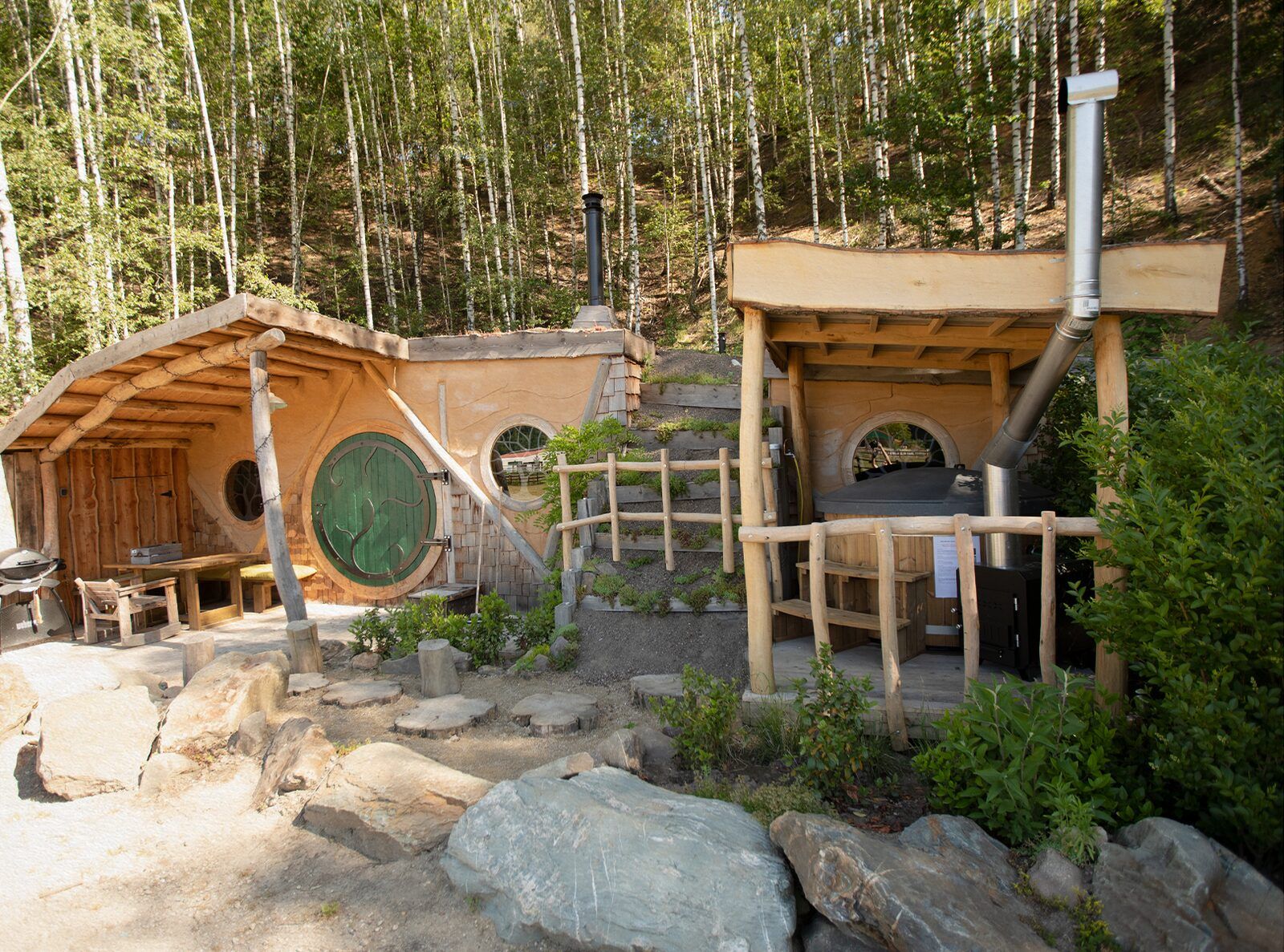 Hobbit House 1 in Neeroeteren, Limburg, Belgie, een uniek vakantiehuis met houten veranda, omgeven door groene natuur en rustieke charme.