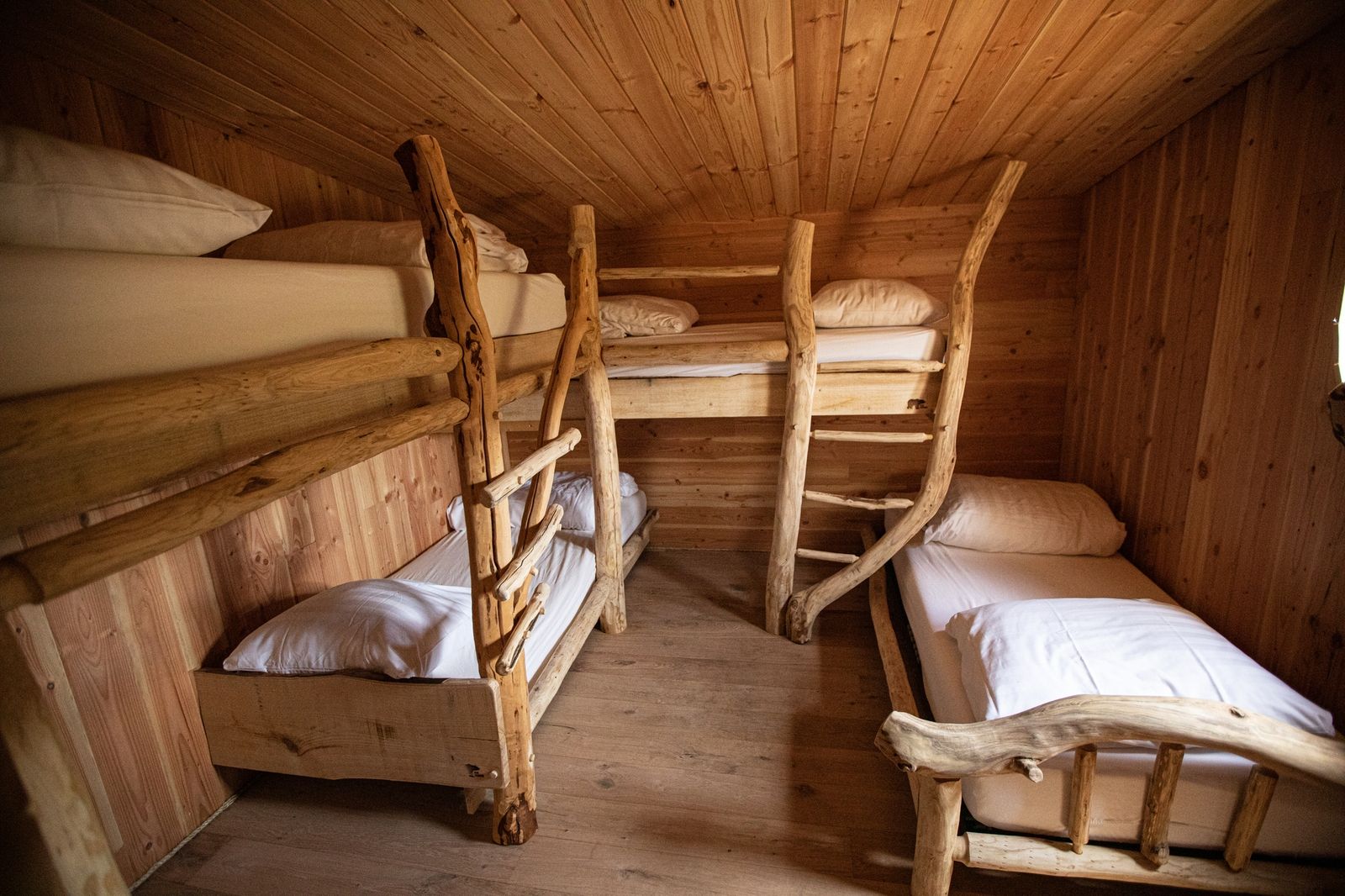 Gezellige slaapkamer in Hobbit House 1, uniek vakantiehuis in Neeroeteren, Limburg, Belgie, met rustieke houten stapelbedden.