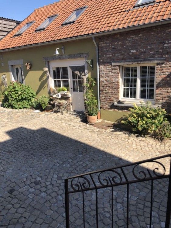 Charmante binnenplaats van vakantiehuis FreLune in Tongeren, Limburg, Belgie met rustieke stenen en groene accenten.