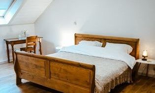 Sfeervolle slaapkamer in FreLune, Tongeren, met houten bed en bureau, biedt rust en comfort in Limburg.