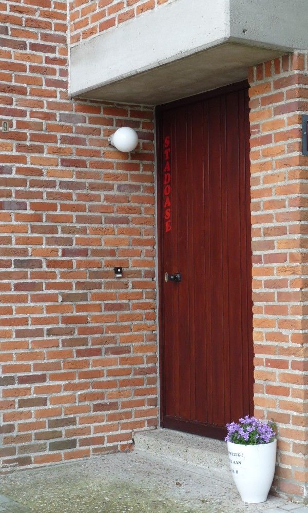 Entree van StadOase-Hasselt vakantiehuis in Limburg, Belgie met houten deur en bloempot.