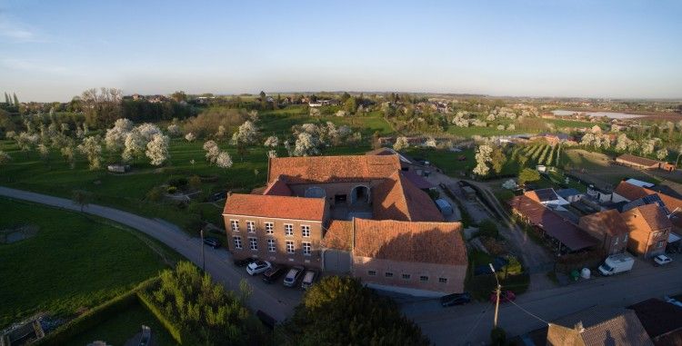 Luchtfoto van Servaeshoeve - Gerstebaard, een vakantiehuis in het pittoreske Borgloon, Limburg, omgeven door bloeiende boomgaarden en groene velden.