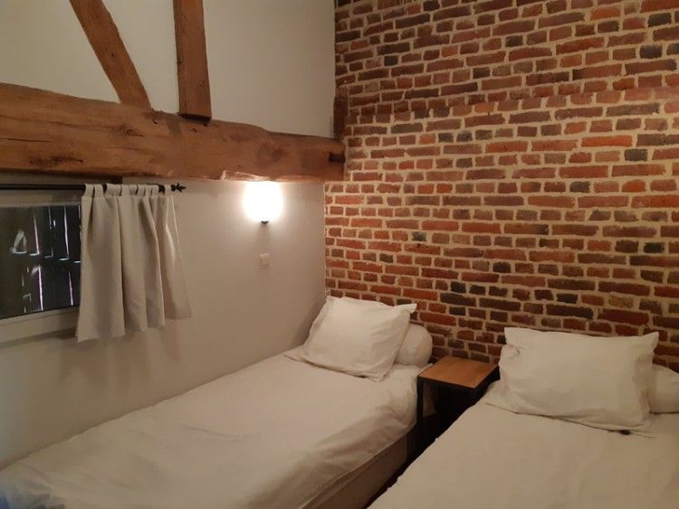 Gezellige slaapkamer in Servaeshoeve - Gerstebaard, vakantiehuis in Borgloon, Limburg, Belgie met rustieke bakstenen muur en houten balken.