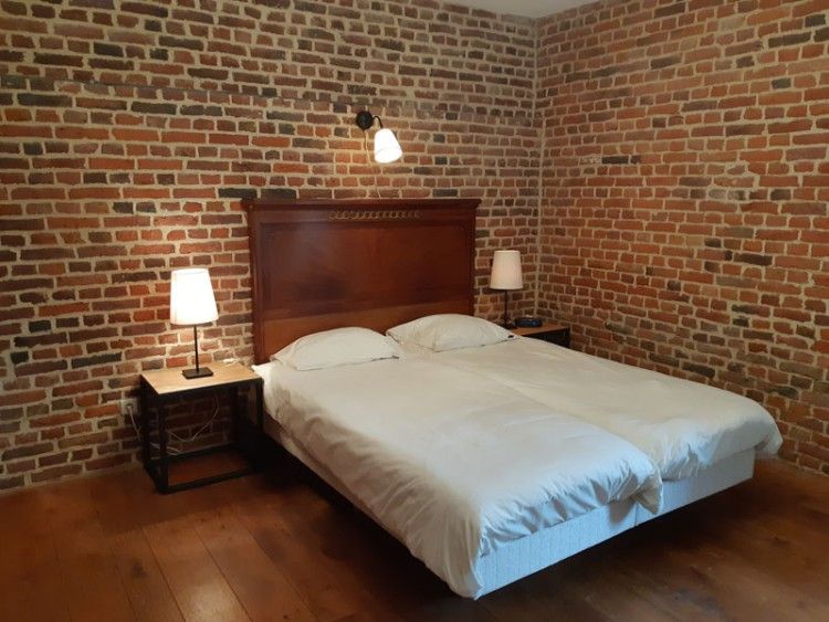 Gezellige slaapkamer in Servaeshoeve - Gerstebaard, een vakantiehuis in Borgloon, Limburg met rustieke bakstenen muren en sfeervolle verlichting.