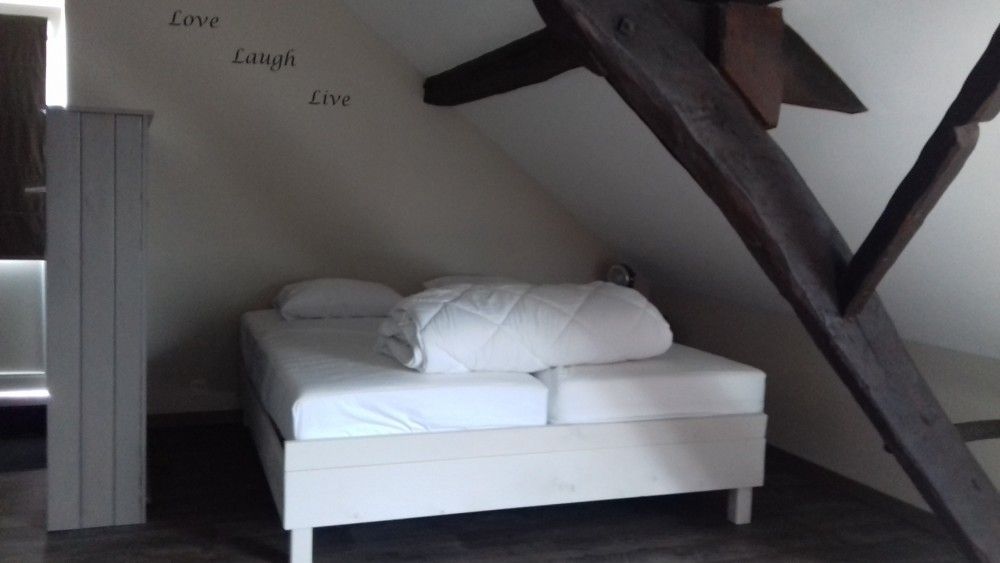 Sfeervolle slaapkamer met houten balken in Aan Maas & Grens vakantiehuis in Kinrooi, Limburg, Belgie.