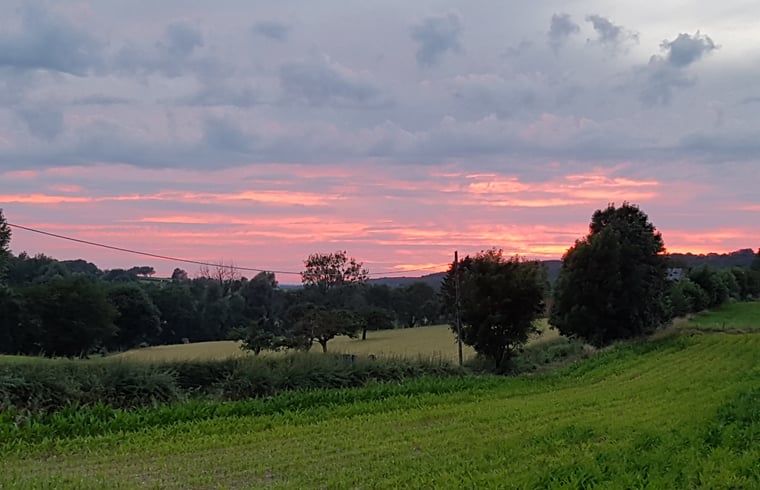 Adembenemend uitzicht op zonsondergang bij Huisje in Sint Pietersvoeren, vakantiehuis in Limburg, Belgie, omgeven door weelderige natuur.