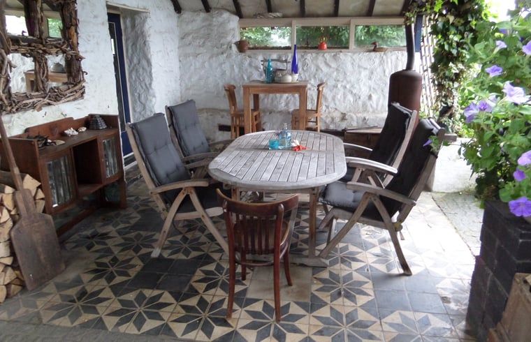Gezellige veranda van Huisje in Sint Pietersvoeren, vakantiehuis in Limburg, Belgie, met rustieke houten meubels en natuurstenen muren.
