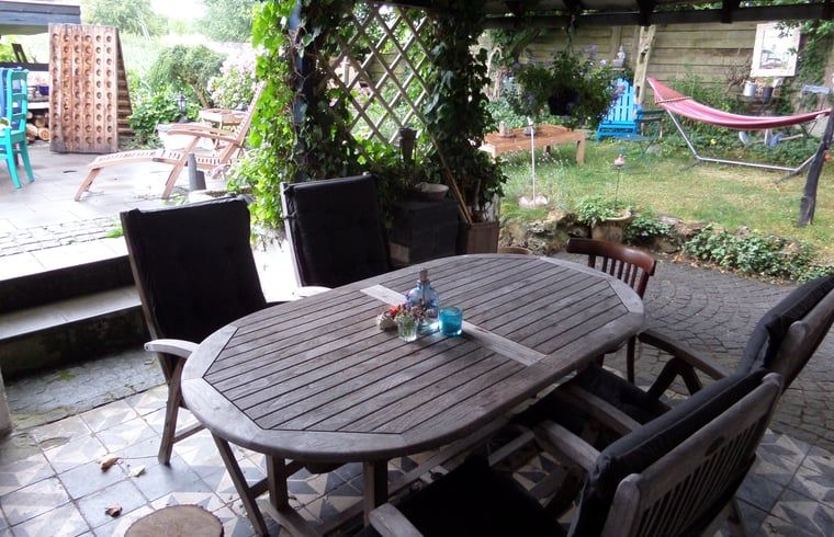 Ontspannen terras van Huisje in Sint Pietersvoeren, vakantiehuis in Limburg, Belgie, met uitzicht op groene tuin en comfortabele zitplaatsen.