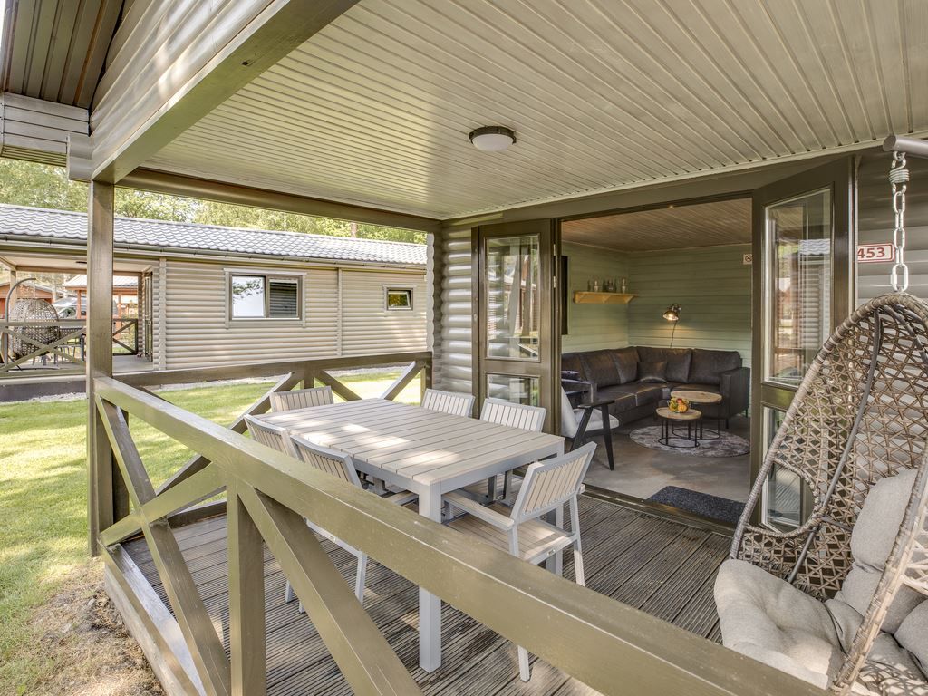 Veranda van Mooi Zutendaal chalet in Limburg, Belgie, met buitenzitje en uitzicht op groene omgeving.