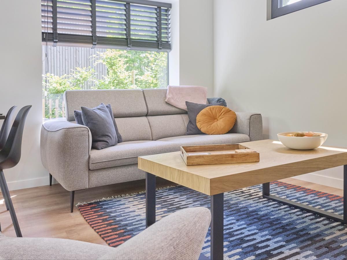 Gezellige woonkamer in De Eekhoorn vakantiehuis, Zutendaal, met comfortabele bank en uitzicht op de tuin.