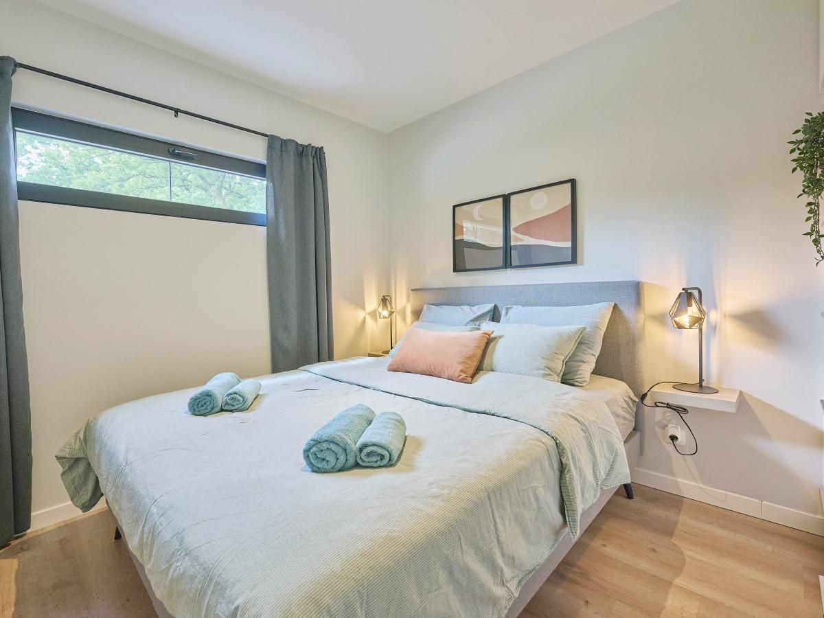 Sfeervolle slaapkamer in De Eekhoorn vakantiehuis, Zutendaal, met knusse verlichting en comfortabele bedden.
