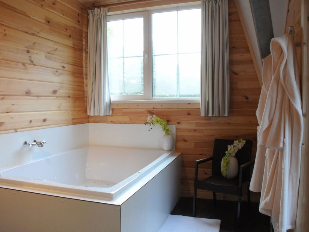 Ontspan in de luxe badkamer van Mooi Zutendaal 4-persoons bungalow in Zutendaal, Limburg, Belgie, met een ruim bad en houten interieur.