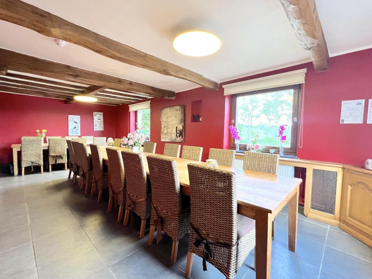 Grosses Esszimmer im Ferienhaus Aux Hirondelles in Malmedy, Ardennen, mit Holztischen und Stuehlen.
