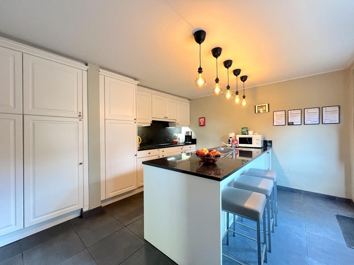 Moderne Kueche des Ferienhauses Aux Hirondelles in Malmedy, Ardennen, mit Bar und Beleuchtung.