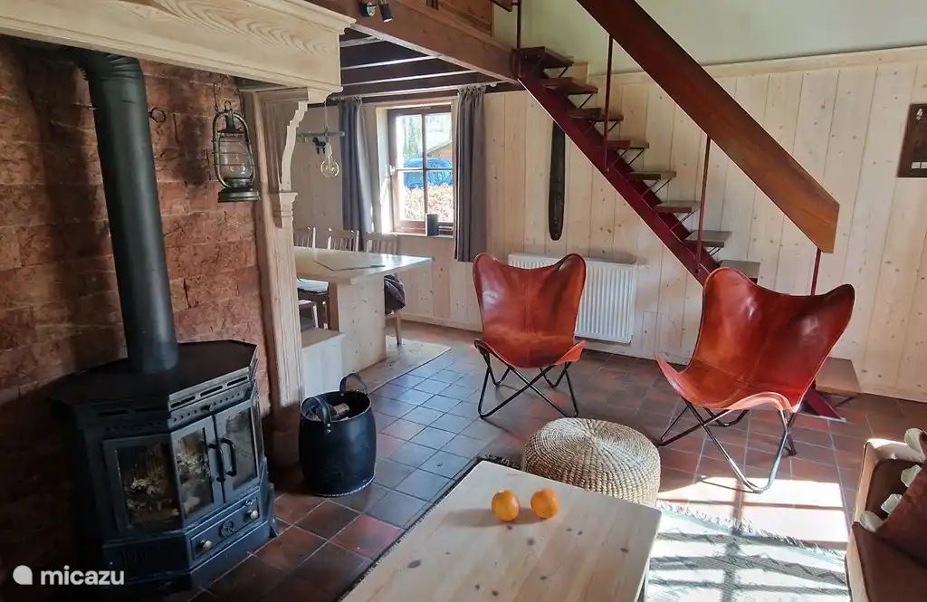 Gemuetliches Wohnzimmer im Chalet Pont du Waud in Waimes, Ardennen, Belgien, mit Holzofen und rustikaler Einrichtung fuer einen gemuetlichen Urlaub.