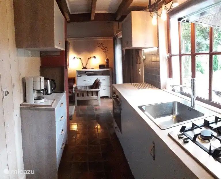 Gemuetliche Kueche im Chalet Pont du Waud, einem Ferienhaus in Waimes in den Ardennen, Belgien, mit Blick auf die gruene Natur durch grosse Fenster.