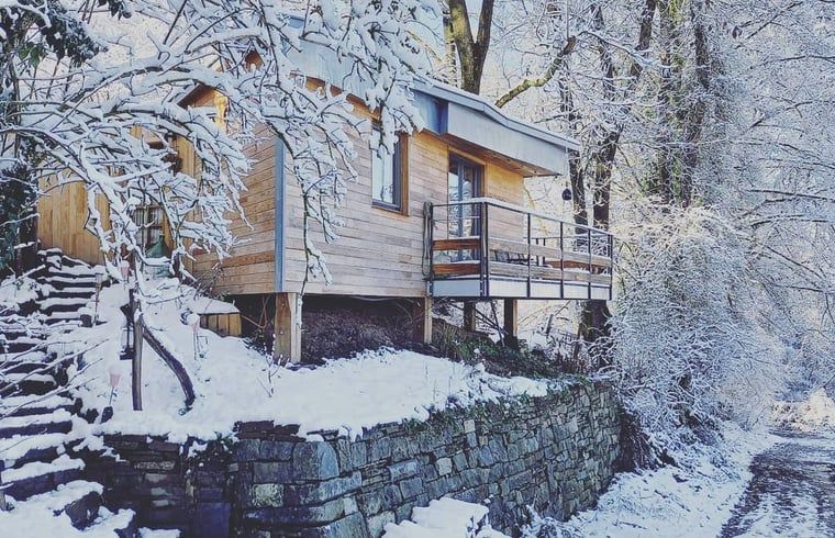 Schnee bedeckt die Huette in Comblain au Pont, einem charmanten Holzferienhaus in den winterlichen Ardennen, Luettich, Belgien.