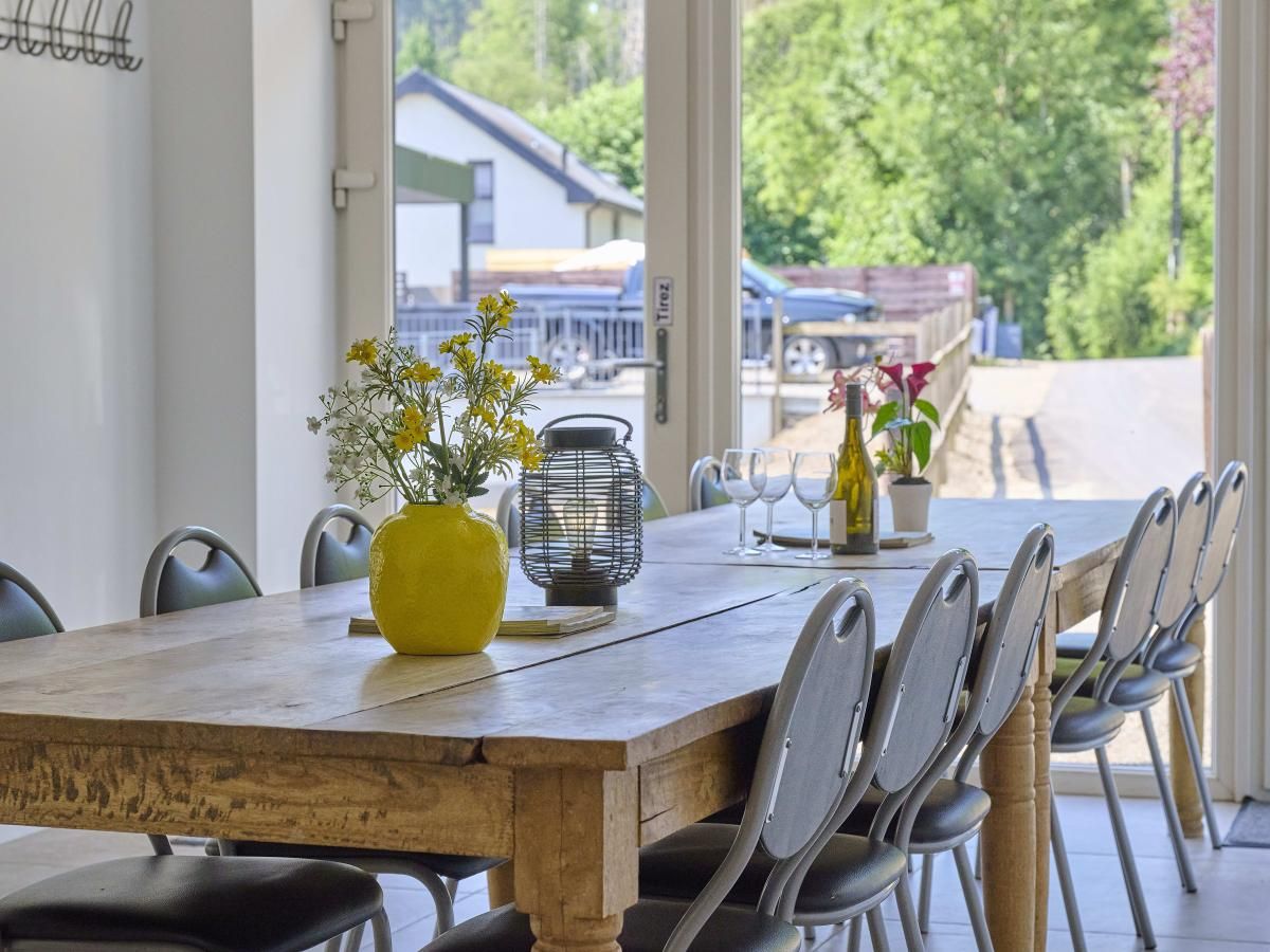 Geniessen Sie das geraeumige Esszimmer im Ferienhaus "La Ferme" in Lierneux in den Ardennen, Belgien, mit herrlichem Blick auf die umliegende Natur.