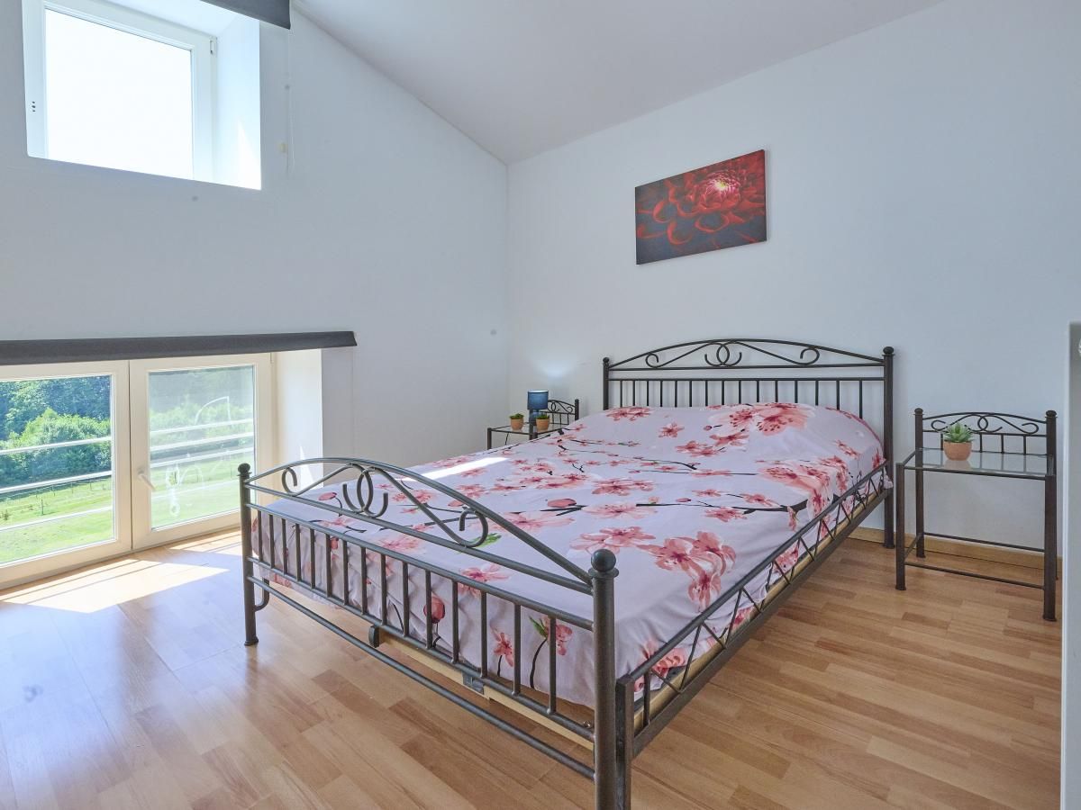 Gemuetliches Schlafzimmer im Ferienhaus "La Ferme" in Lierneux, Ardennen, Belgien. Helles Interieur mit Blick auf die gruene Umgebung.