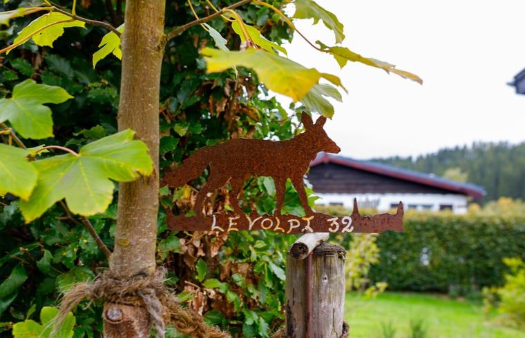 Das Ferienhaus in Kuechelscheid in den Ardennen, Belgien, bietet einen charmanten Aussenbereich mit einem gruenen Garten und einer rustikalen Holzfassade.