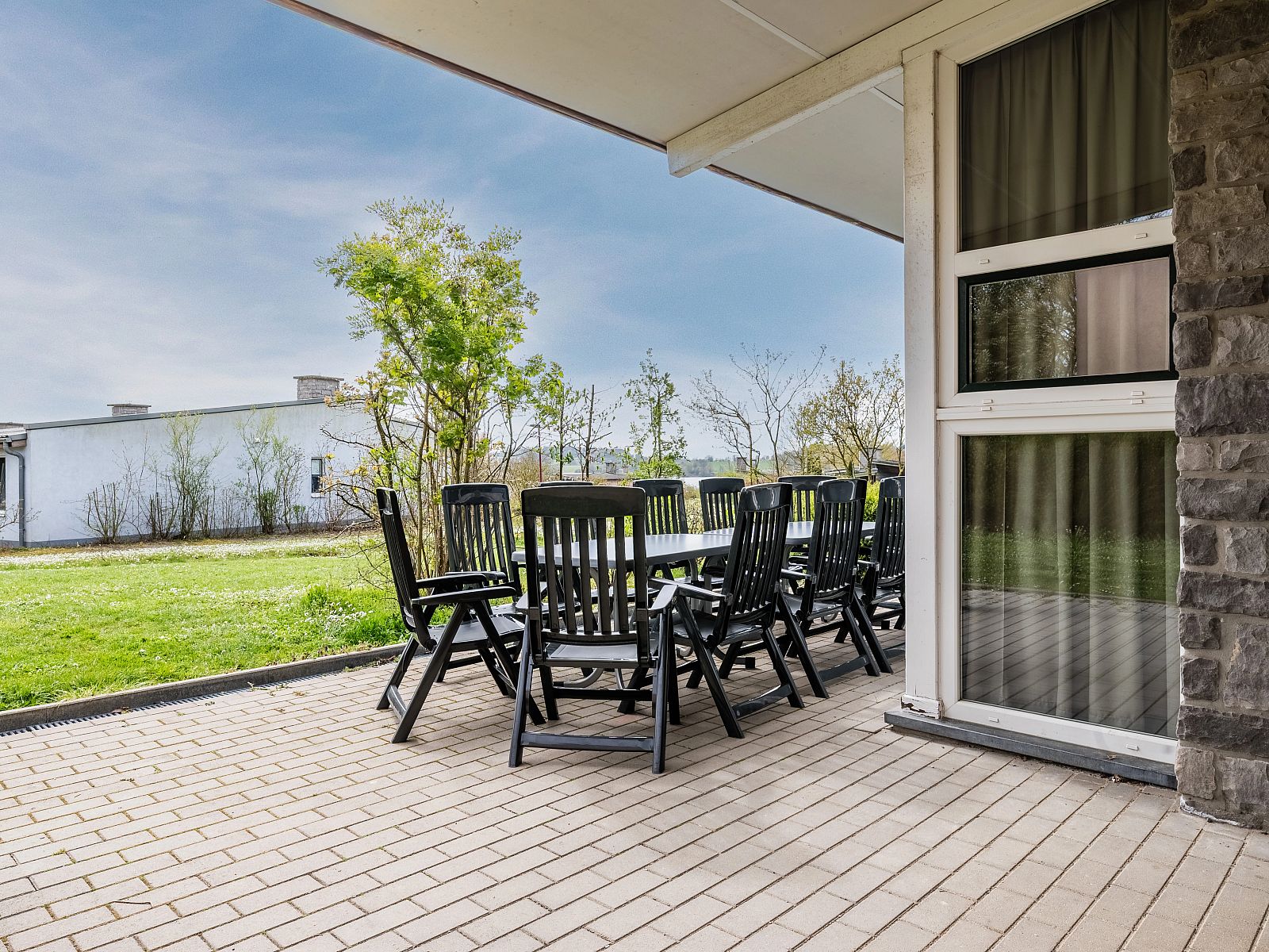 Ruim terras van Village l'Eau d'Heure 12-persoons bungalow in Froidchapelle, Henegouwen, Belgie, met comfortabel tuinmeubilair en uitzicht op groen.