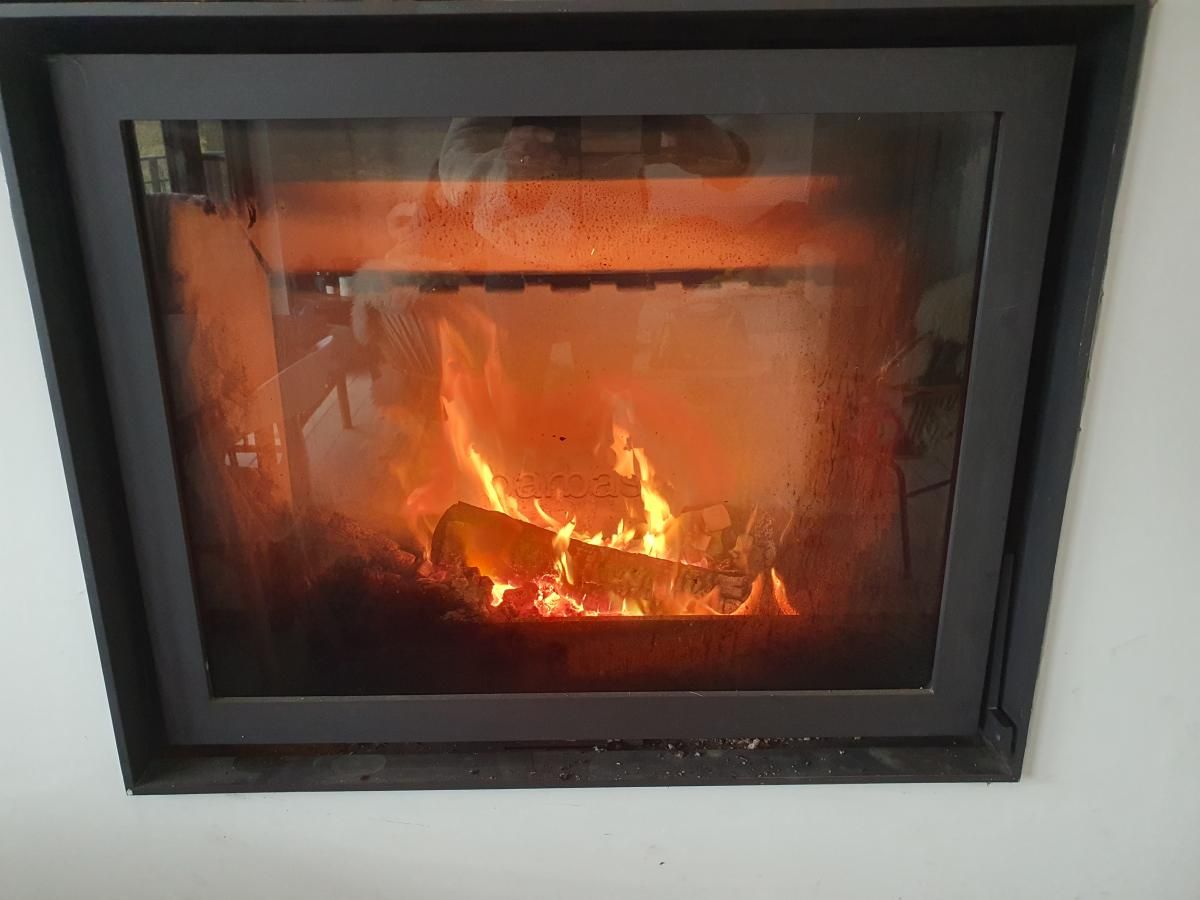 Cozy fireplace in chalet Agathe, Laforet, Ardennes, Belgium, offers warmth and atmosphere for a relaxing vacation stay.