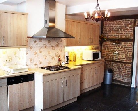 Moderne keuken in Les Gronsarts Vencimont vakantiehuis met houten kasten en bakstenen details in Vencimont, Ardennen.