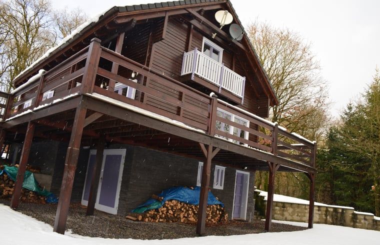 Gemuetliches Ferienhaus in Heure, Ardennen, Belgien mit Holzveranda und winterlichem Charme, ideal fuer einen entspannten Aufenthalt in der Natur.